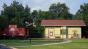 Photo of red train caboose parked next to yellow train depot.