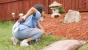 Photo of a woman massaging her back next to some much and landscaping.
